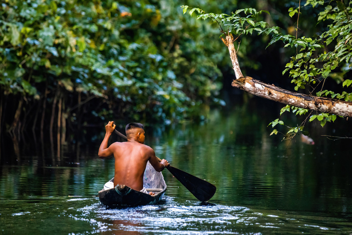 Native Tribal Man in Amazonia Rainforest in Handmade Boat